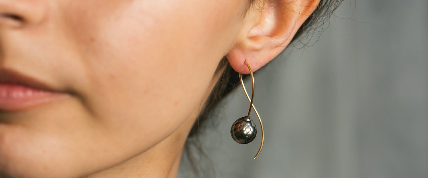 Model wearing yellow gold and faceted Tahitian pearl earring
