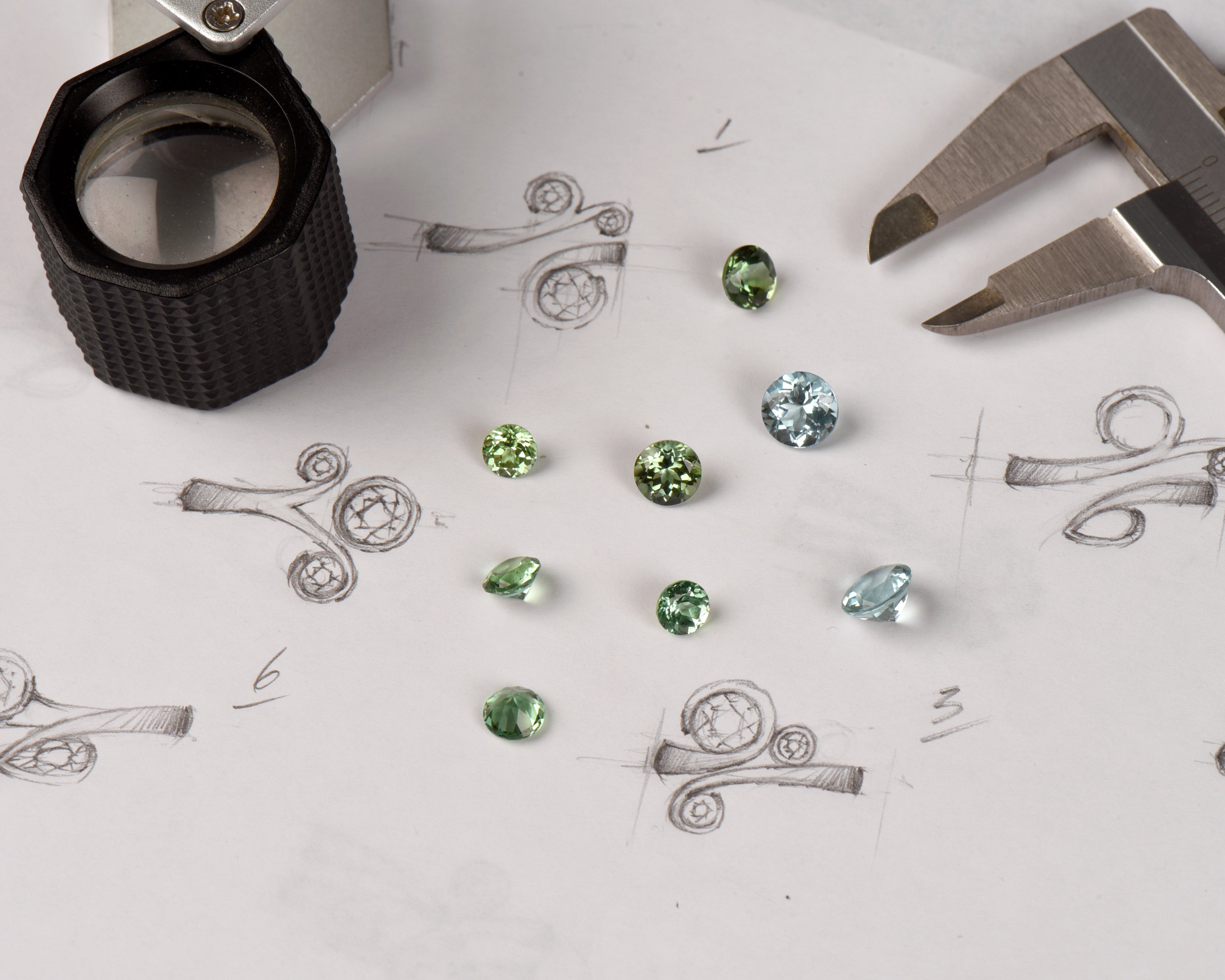 bespoke jewellery design sketches and green gemstones with jewellery tools