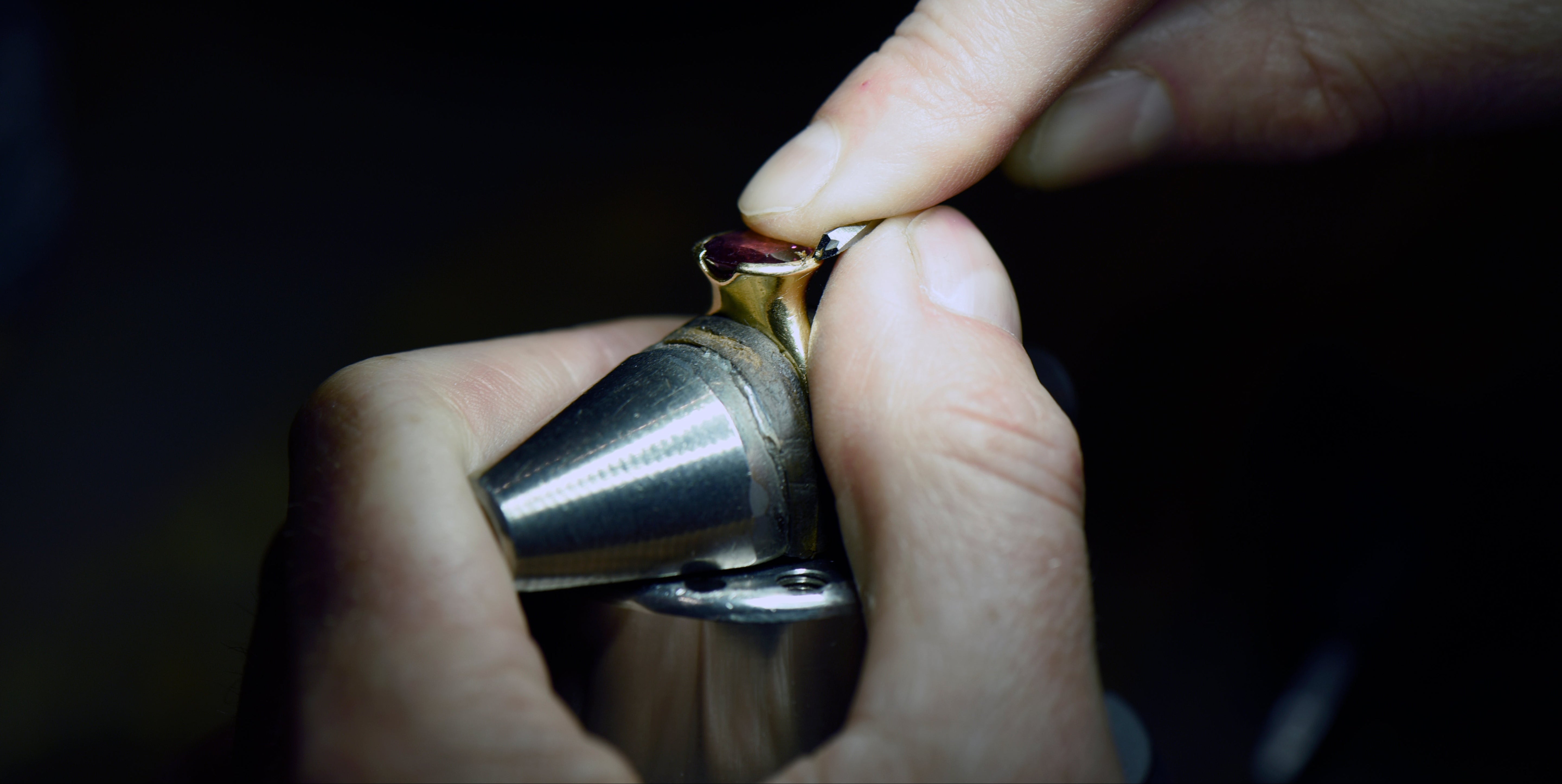 jeweller setting a garnet into an engagement ring with jewellery tools